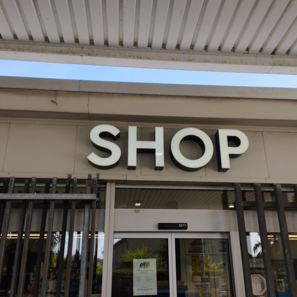 Illuminated profile letters spelling out SHOP on the façade of the BFT petrol station in Hünxe.